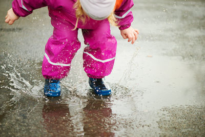 Low section of girl standing in puddle