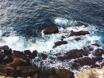 High angle view of waves splashing on rocks