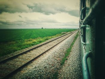 Railroad track amidst field against sky