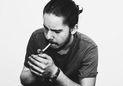 Close-up of man smoking against white background