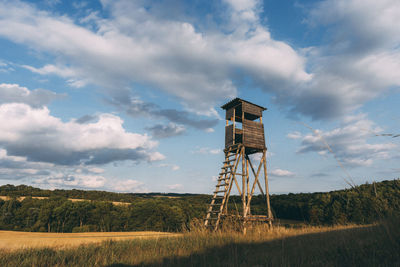 Water tower on field against sky