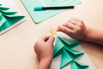 High angle view of hand holding paper painting on table