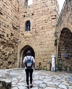 Rear view of man standing against brick wall