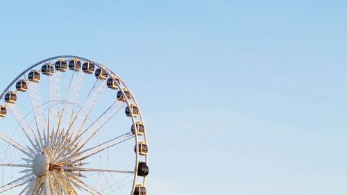 Low angle view of ferris wheel against clear blue sky