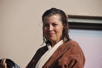 Portrait of smiling mature woman standing against house