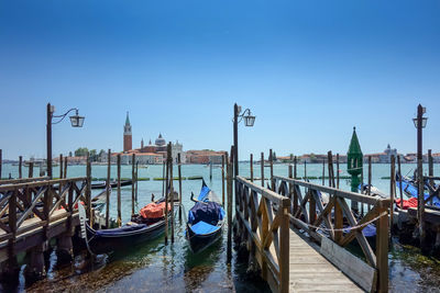 Gondolas moored on grand canal against clear blue sky