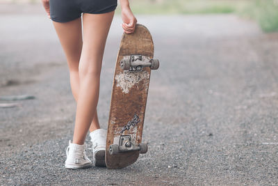 Low section of woman walking with skateboard