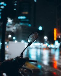 Close-up of person holding wet illuminated street at night