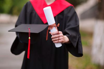 Midsection of male university student holding degree