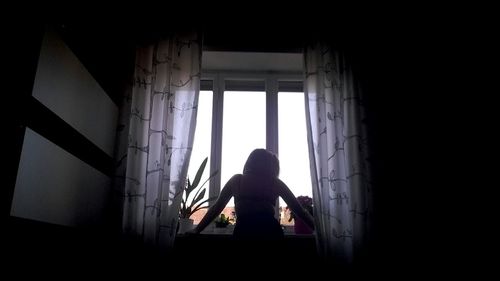 Rear view of woman looking through window