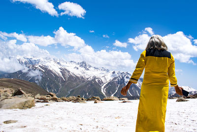 Rear view of woman standing on mountain against sky