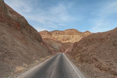 Road amidst rocks in desert against sky