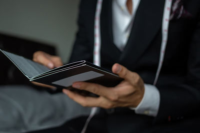 Midsection of tailor holding paper