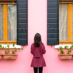Rear view of woman standing against window
