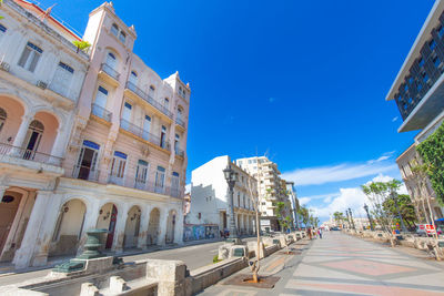 Road amidst buildings against blue sky