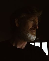 Portrait of man looking away against black background