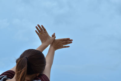 Rear view of woman gesturing against sky