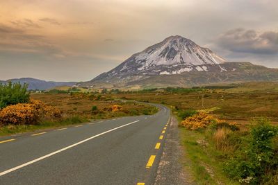 Empty road along landscape and mountains against sky