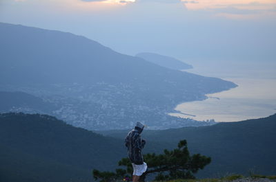 Rear view of people looking at mountains against sky