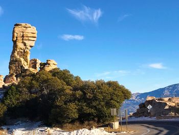 Rock formations by buildings against blue sky