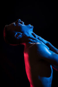 Close-up of shirtless man against black background