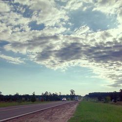 Road on field against cloudy sky