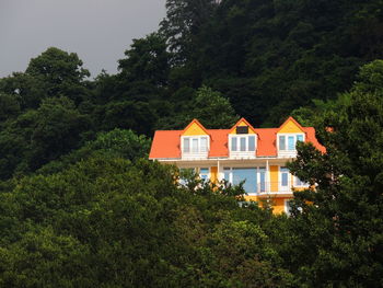 House and trees by building against sky