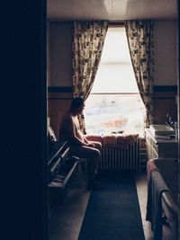 Side view of naked man sitting on table in apartment