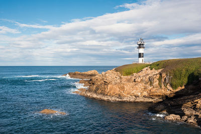 Lighthouse amidst sea and buildings against sky