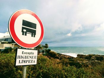 Information sign by road against sky