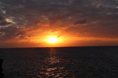 Scenic view of sea against dramatic sky during sunset