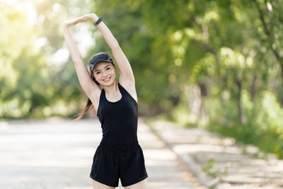 Portrait of young woman standing against tree