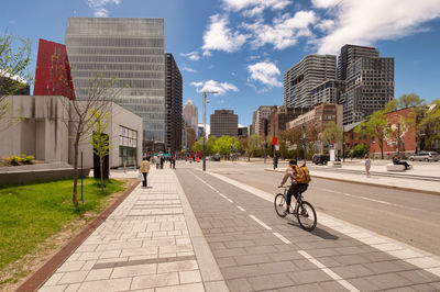 People riding bicycle on street amidst buildings in city