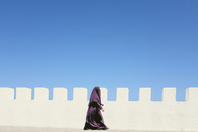 Rear view of woman standing against blue sky