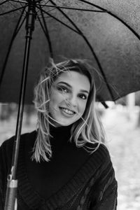 Close-up of young woman holding umbrella during rain