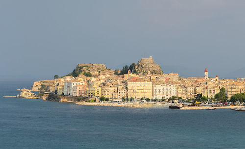 Scenic view of sea by city against clear sky