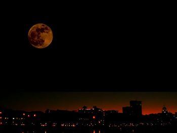 Illuminated cityscape against clear sky at night