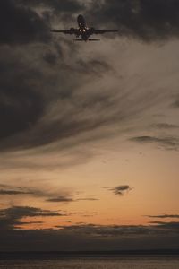 Low angle view of silhouette man in sea against sky during sunset