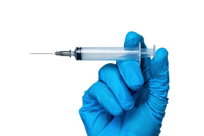 Close-up of hand holding blue umbrella against white background