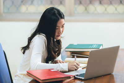 Woman using phone while sitting on table