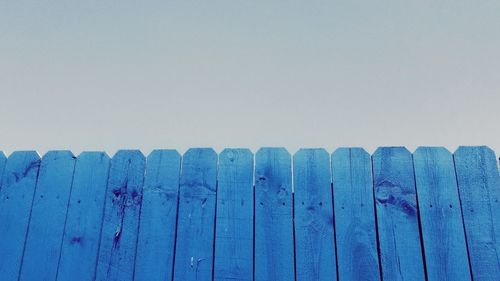 Low angle view of blue fence against clear sky