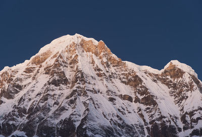 Low angle view of snowcapped mountain against clear sky