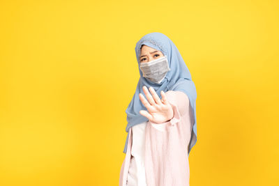 Portrait of woman standing against yellow background