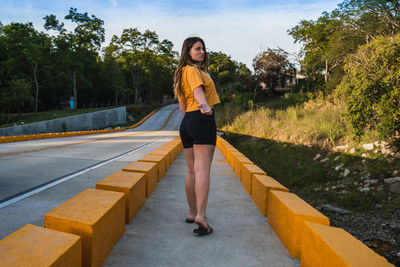 Full length of woman standing on road against trees