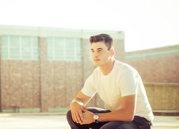 Young man sitting on sunglasses outdoors