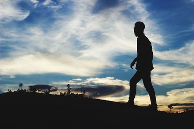 Low angle view of silhouette man standing against sky during sunset