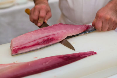 Japanese cook cutting large piece of tuna fish