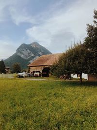 Houses on field by mountains against sky