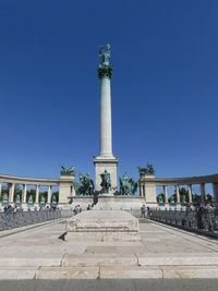 Statue in city against clear blue sky