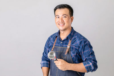 Portrait of young man holding globe against white background